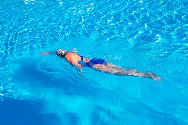 Woman with swimsuit swimming on a blue water pool.