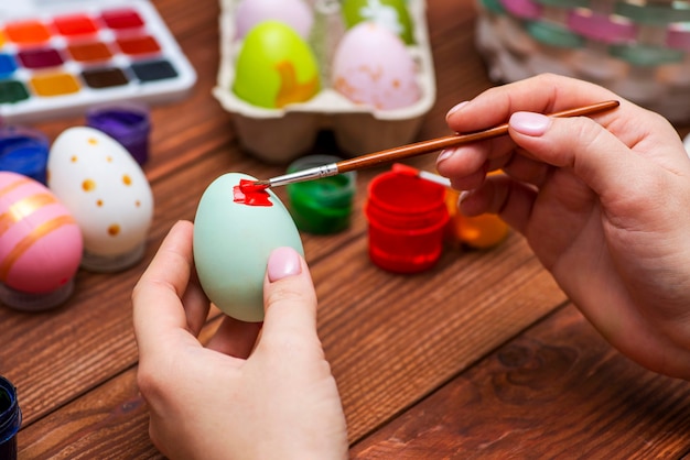 A woman with a tassel paints Easter eggs