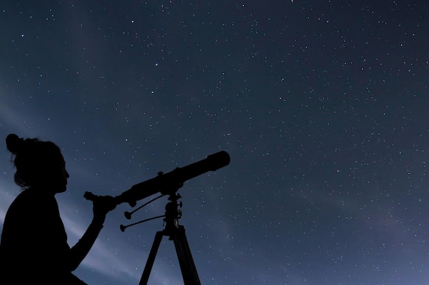 Woman with telescope watching the stars. Stargazing woman and night sky.