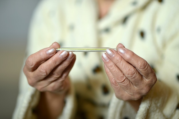 Woman with thermometer in her hand close-up