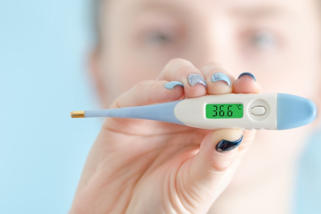 Woman with a thermometer in his hand. Normal body temperature: 36.6