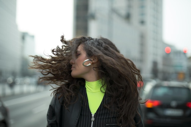 Photo woman with tousled hair against buildings in city