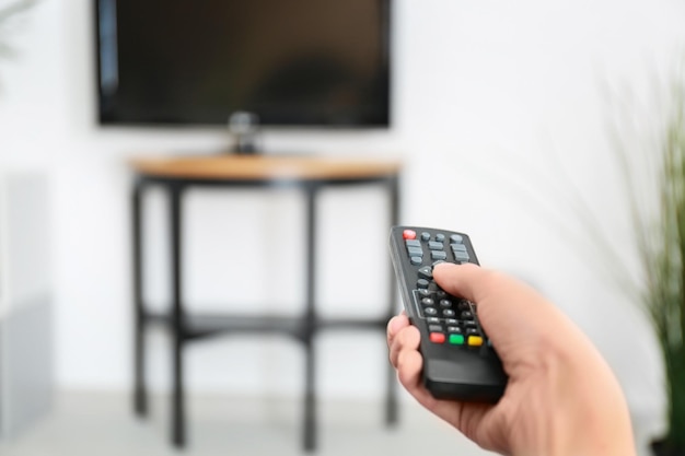 Woman with TV remote control switching channels closeup