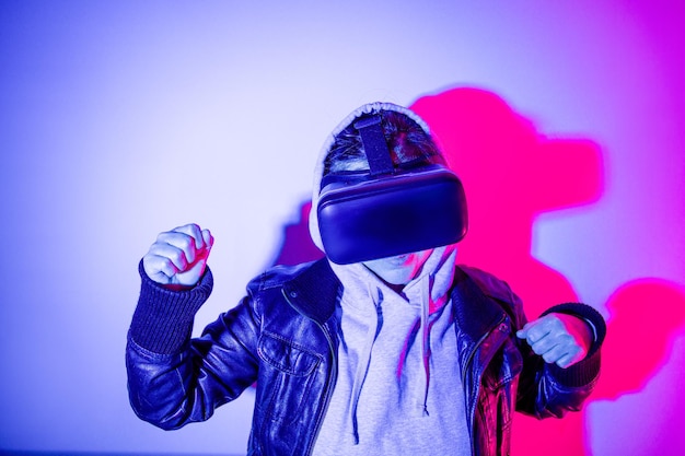 Woman with virtual reality goggles dancing in colorful metaverse