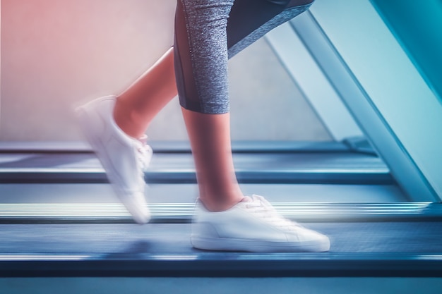 Woman with white shoes is fast walking on treadmill with motion blur effects