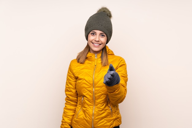 Woman with winter hat over wall handshaking after good deal