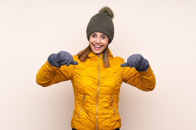 Woman with winter hat over wall proud and self-satisfied