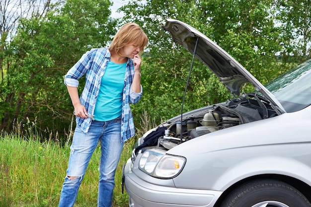 Woman with wrench near broken car