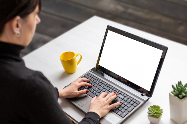 Woman work on laptop with isolated screen on white flat desk with cup of coffee and plants