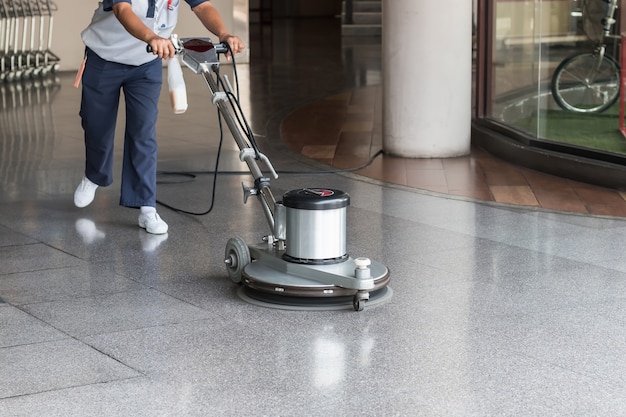 Woman worker cleaning the floor with polishing machine