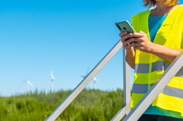 Photo woman worker in a wind farm green energy technical review with the phone in her hand