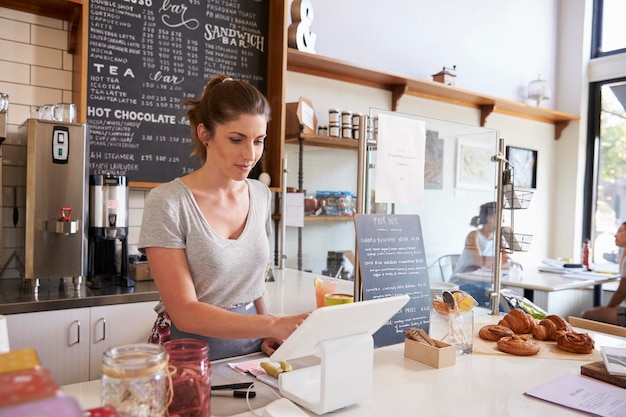 Woman working on the till at a coffee shop wide angle