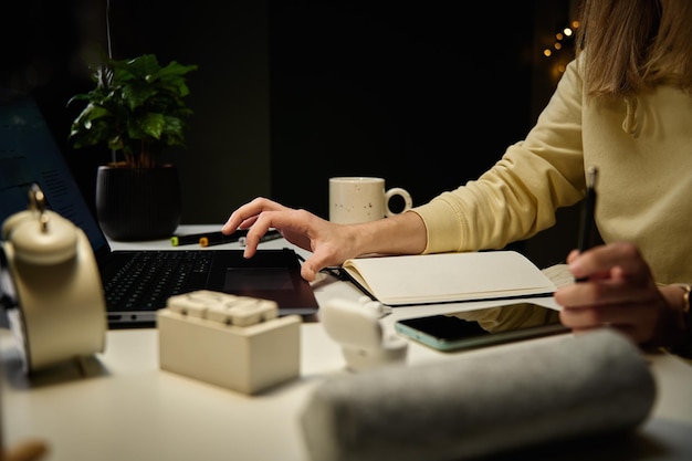 Woman working from home workplace at night using laptop