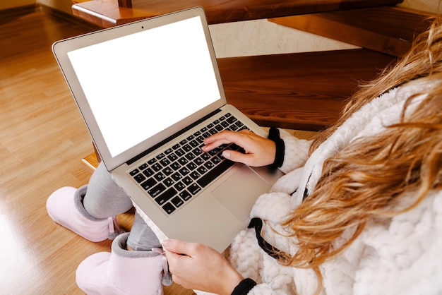 Woman working at home sitting in chair with laptop