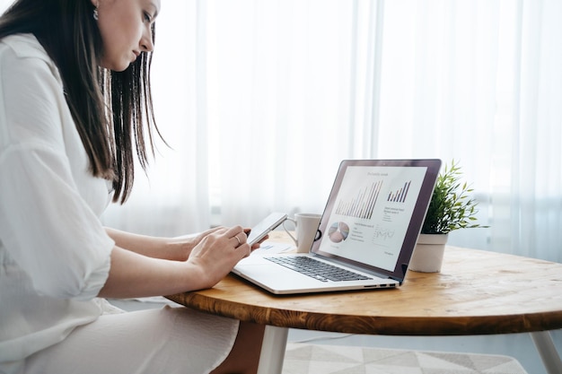 Woman working on a laptop and reading a text message in her apartment