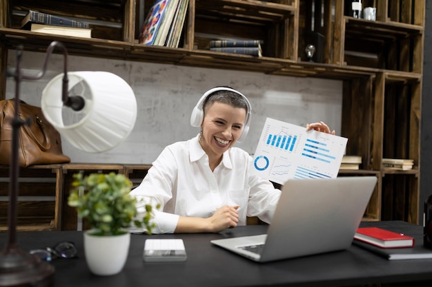 Woman working on a laptop using headphones in headphones demonstrates a graph on the screen