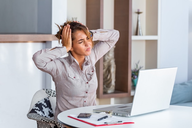 Woman working at office desk suffering from headache