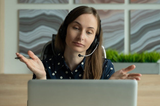 Woman working online with headset and laptop in office