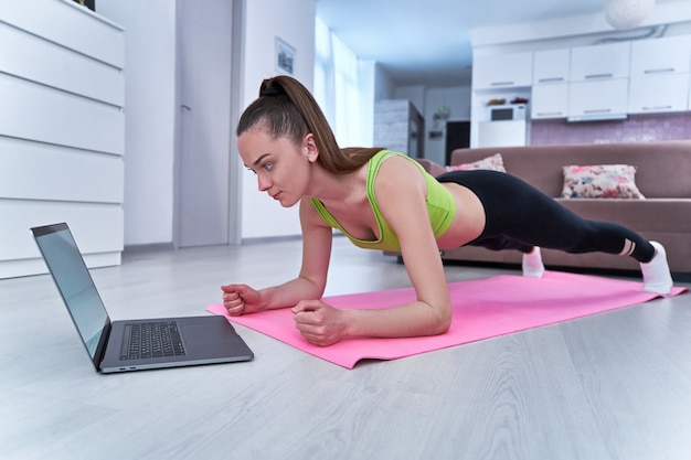 Woman working out at home using her laptop