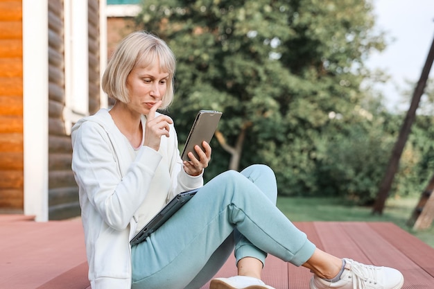 Woman working in park with phone and laptop Businesswoman works outdoor green nature background Wi fi network connection free access Freelancer Relaxing In Nature And Using Technology