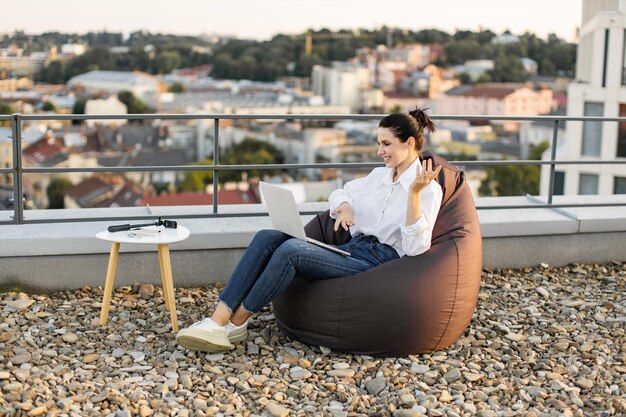 Photo woman working on rooftop with laptop and modern city view