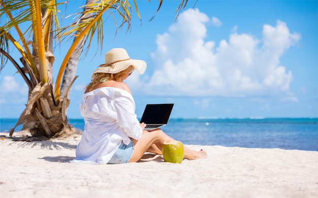 Woman working with laptop computer on the tropical beach concept of working anywhere