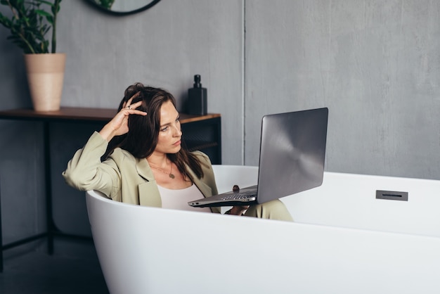 Woman works in the bathtub with her laptop in the privacy of her home.