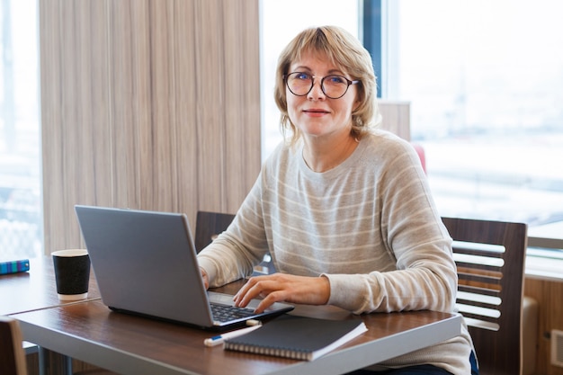 A woman works at a laptop in the office at the workplace . She reads on the computer.