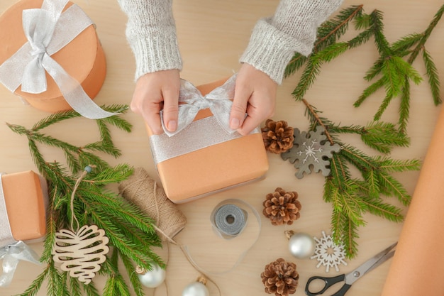 Woman wrapping gift for Christmas on table