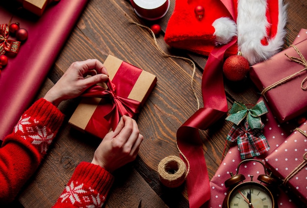 Woman wrapping gift on wooden table