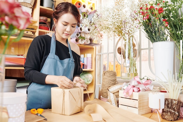 Woman wrapping presents in flower shop