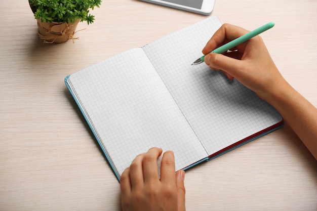 Woman write on notebook on workplace close up