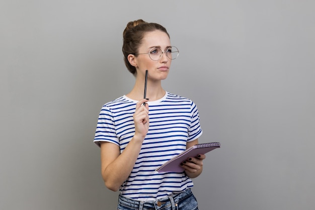 Woman writing business idea future plans looking away with thoughtful expression