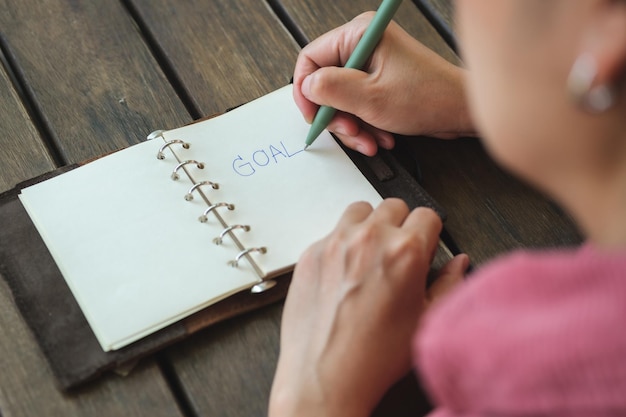 Woman writing goal on notebook  at coffee shop outdoor space