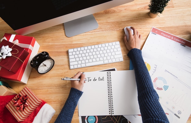 woman writing to do list in christmas holiday at the office with christmas decoration on table.