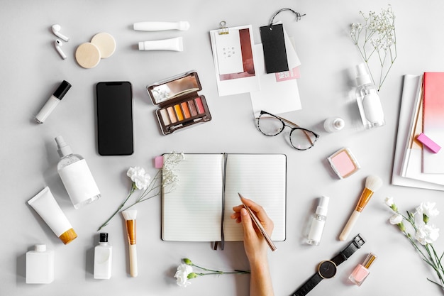 Woman writing on a notebook surrounded by beauty products