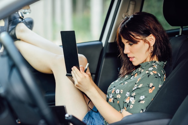 Woman writing in a notebook with a pen in a white car