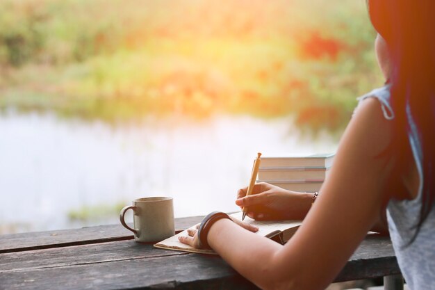 woman writing notebook on wood table.