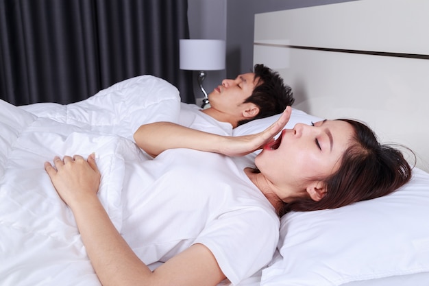 woman yawning and her husband sleeping on bed