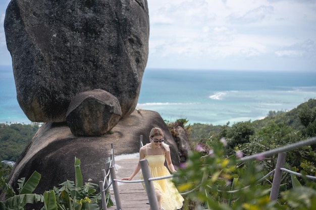 Woman in yellow dress walking to overlap with ocean view background.