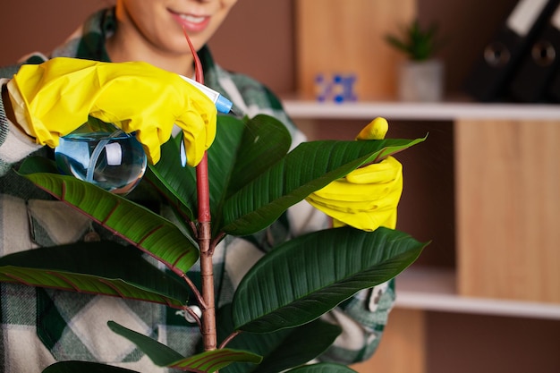 Woman in yellow gloves looking after houseplants at home