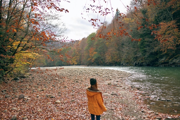 Woman in a yellow jacket near the river mountains nature walk