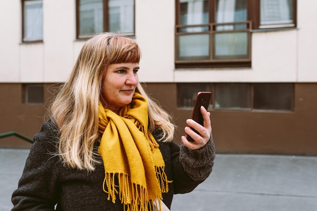 A woman in a yellow scarf looks at her phone