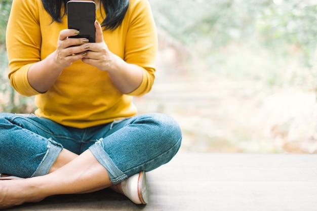 Woman in yellow shirt holding a black Mobile phone