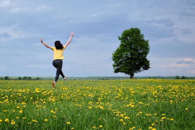 Woman in a yellow t-shirt moves across the field with flowers