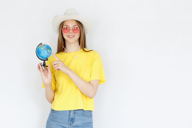 A woman in a yellow T-shirt shows on the globe on a gray background. holidays and tourism