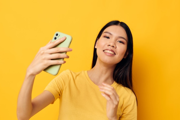 Woman in a yellow tshirt looking at the phone posing studio model unaltered