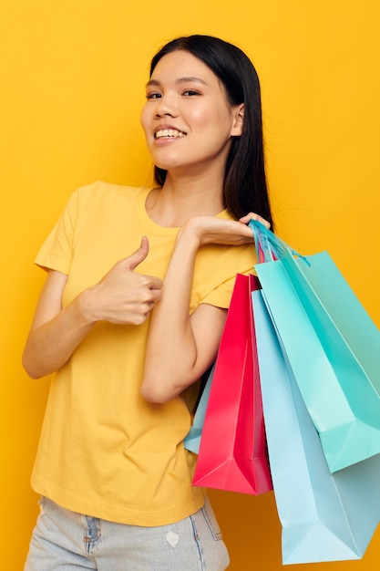 Woman in a yellow Tshirt with multicolored shopping bags isolated background unaltered