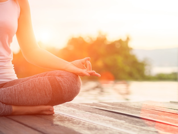 Woman yoga finger acting on hands in front of sea with nature surrounding background