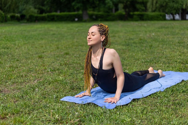 Woman yogi with dreadlocks practicing Upward Facing Dog Pose Urdhva Mukha Svanasana pose on yoga mat